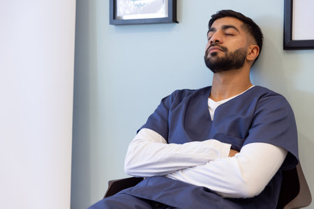 Biracial male doctor taking nap in hospital waiting room. Medicine, healthcare and medical services, unaltered.の写真素材