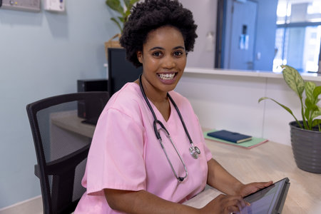 Portrait of african american female doctor using tablet in hospital reception. Medicine, healthcare, communication and medical services, unaltered.の写真素材