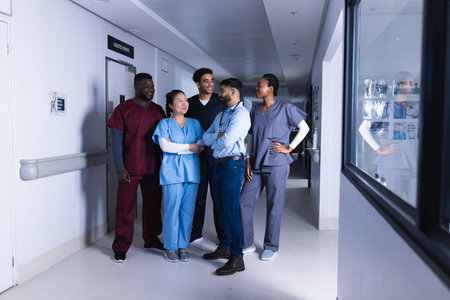 Happy diverse male and female doctors talking in hospital corridor. Medicine, healthcare and medical...