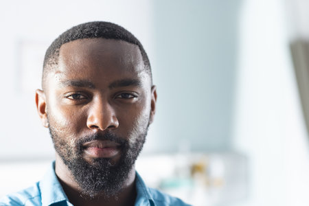 Portrait of african american male doctor in sunny hospital room. Medicine, healthcare and medical services, unaltered.の写真素材