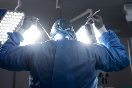 Back of african american female doctor wearing face mask in hospital operating room. Medicine, healthcare and medical services, unaltered.の写真素材