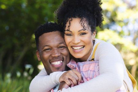 Happy african american couple embracing in sunny garden, copy space. Outdoors, expression, love,...