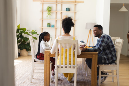 Happy african american family having fresh fruits snack in dining room at home, copy space. Togetherness, parenthood, childhood, food and drink, domestic life and healthy lifestyle, unaltered.の写真素材