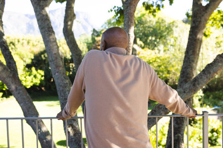 Back of african american senior man on sunny terrace. Lifestyle, retirement, senior lifestyle, nature and domestic life, unaltered.の写真素材