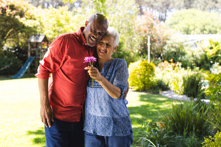 Happy diverse senior couple embracing in sunny garden. Lifestyle, retirement, senior lifestyle, nature, togetherness and domestic life, unaltered.の写真素材
