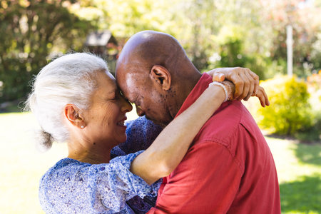 Happy diverse senior couple hugging in sunny garden. Lifestyle, retirement, senior lifestyle,...