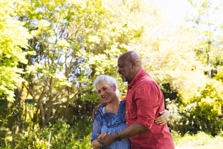 Happy diverse senior couple dancing in sunny garden. Lifestyle, retirement, senior lifestyle,...