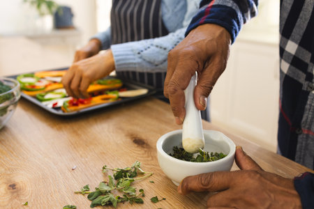 Hands of diverse senior couple preparing healthy meal with vegetables in kitchen. Lifestyle, retirement, senior lifestyle, food, cooking, togetherness and domestic life, unaltered.の写真素材
