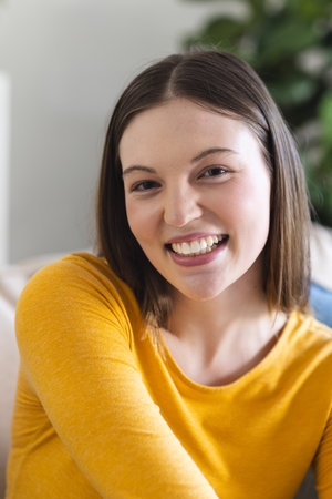 Portrait of happy caucasian woman sitting on couch in living room at home, copy space. Expression...