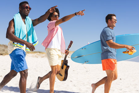Diverse friends enjoy a sunny beach day. They carry surfboards and a guitar, highlighting a fun and...