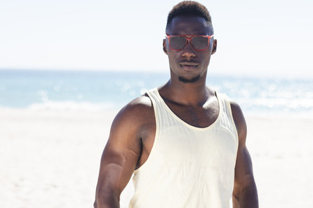 A young African American man stands on the beach. He enjoys the sunny outdoor setting by the ocean unaltered.の写真素材