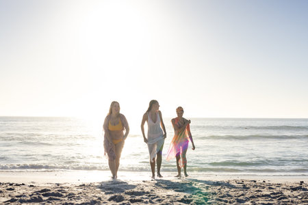 Three young women enjoy a sunny day at the beach. The group's leisure time adds a sense of relaxation and friendship to the outdoor setting.の写真素材