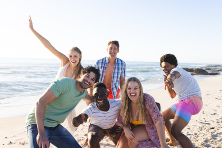 Diverse group of friends enjoy a day at the beach. Smiling and posing for a photo, they capture the essence of summer fun outdoors.の写真素材