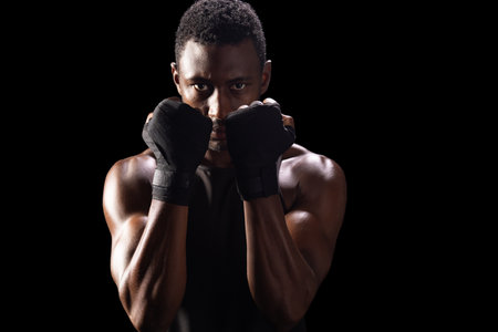 African American man in a boxing stance, with copy space. His focused expression and muscular build convey strength and determination.の写真素材