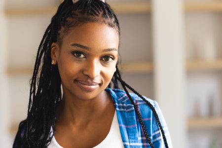 African American young woman wearing casual clothes standing indoors. She has braided hair, brown eyes, and light makeup, unalteredの写真素材