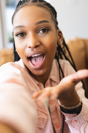 African American young woman with braided hair is talking. She wears light pink shirt and has clear skin, unalteredの写真素材