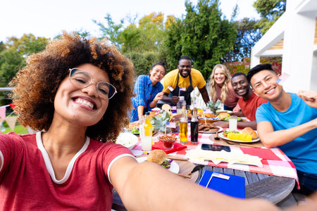Portrait of happy diverse group of friends taking selfie and having dinner with flags of usa. Independence day, tradition, friendship, patriotism, flags and lifestyle, unaltered.の写真素材