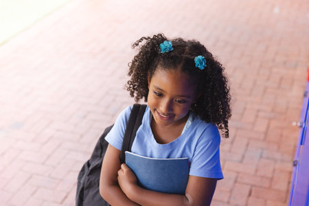 Biracial girl stands ready for school. She holds her books tightly, anticipating a day of learning.の写真素材