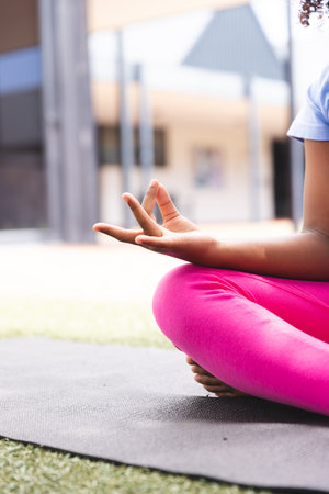 Biracial girl practices yoga outdoors at school, with copy space. Her focus on wellness is evident in the serene setting.の写真素材