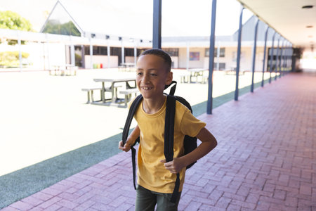 Biracial boy smiles at school, with copy space. His backpack suggests he's ready for a day of learning.の写真素材