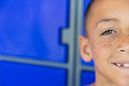 Close-up of a biracial boy smiling in school, with copy space. His freckles and joyful expression brighten the school setting.の写真素材