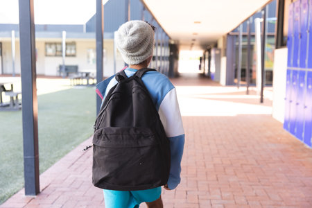 Biracial boy walks through school corridor, with copy space. Backpack on, he's ready for a day of learning and fun at school.の写真素材