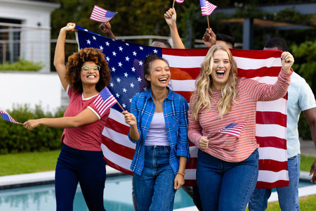 Portrait of happy diverse friends with flags of usa in garden. Independence day, fourth of july, patriotism, friendship, flags and lifestyle, unaltered.の写真素材