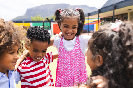 In school, diverse children are huddling together outside, smiling. They have curly hair, boys in striped shirts, the girl in pink dress, unalteredの写真素材