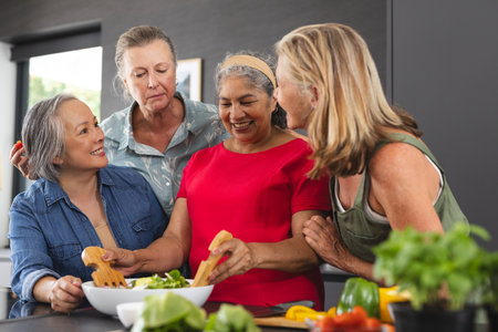 Group of diverse mature women preparing salad together. retirement, friendship, senior living, happiness in modern kitchen with fresh vegetables and bright natural light, unalteredの写真素材