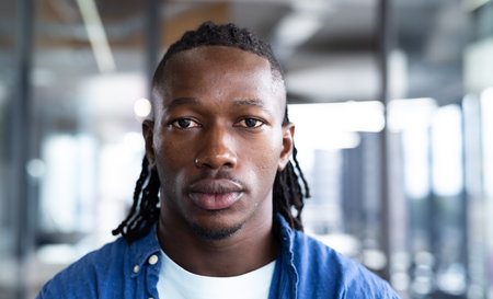 Man in office wearing blue shirt, looking directly at camera, serious expression. Business, professional, corporate, portrait, executive, workplace, formal, unalteredの写真素材