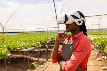 Using VR headset, female farmer inspecting hydroponic vegetable garden in greenhouse, copy space. Agriculture, farming, technology, innovation, organic, sustainable, unalteredの写真素材