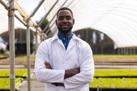 Male scientist in lab coat standing confidently in hydroponic farm greenhouse. hydroponics, agriculture, technology, innovation, unalteredの写真素材