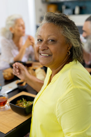 At home, Smiling woman enjoying meal with friends at dining table, sharing moment. Friendship, socializing, celebration, togetherness, cuisine, unalteredの写真素材