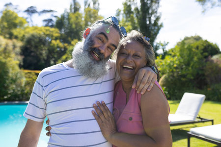 Smiling and embracing, diverse senior friends enjoying time together outdoors. Friendship, seniors, diversity, bonding, happiness, unalteredの写真素材