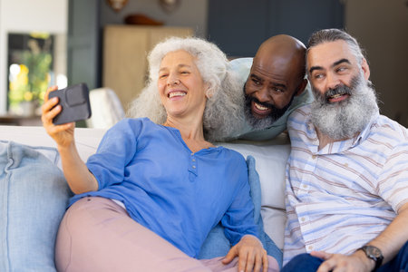 At home, Taking selfie, group of senior friends smiling and sitting on couch indoors. Friendship,...