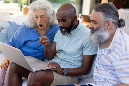 At home, Group of senior friends watching video on laptop, reacting with surprise. Seniors,...