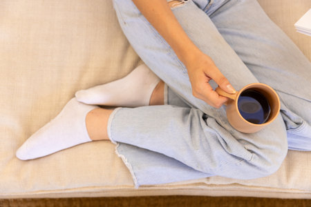 Relaxing at home, woman holding coffee cup while sitting on couch. Relaxation, comfort, lifestyle,...