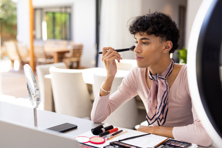 Applying makeup, transgender woman using brush and mirror at home vanity station. Cosmetics, self-care, beauty, lifestyle, gender identity, makeup brushの写真素材