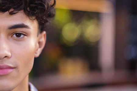 Close-up of teenage boy with curly hair, half face visible, looking confident, copy space. Confidence, portrait, determination, expressive, motivation, self-assuredの写真素材