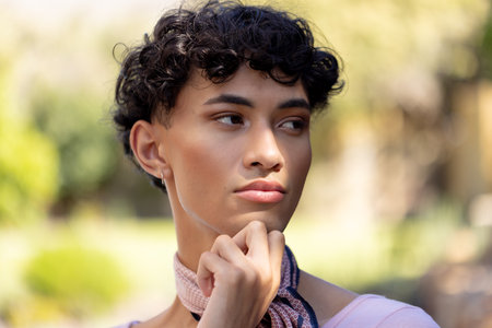 Contemplating outdoors, transgender transgender woman with scarf looking away thoughtfully. LGBTQ,...