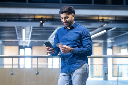 Using smartphone and holding credit card, man making online payment. E-commerce, shopping,...