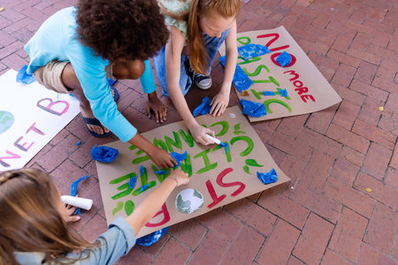 Happy diverse schoolchildren making ecology posters during outdoor school art class. Education, creativity, school, protest, activism and ecology concept.の写真素材