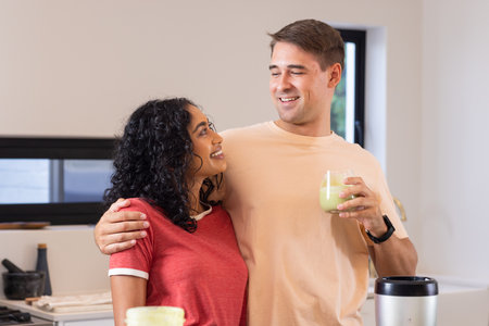 Smiling couple in kitchen enjoying healthy smoothies together, embracing each other. love, happiness, togetherness, wellbeing, nutrition, lifestyleの写真素材