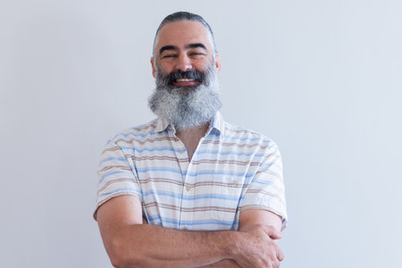 Smiling senior man with arms crossed, wearing striped shirt, looking confident. Elderly, casual, mature, happy, crossed arms, portraitの写真素材
