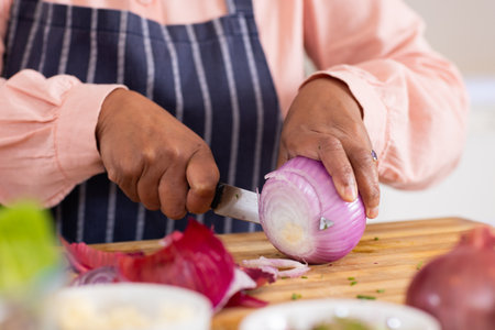 Chopping red onion on wooden cutting board, person preparing ingredients for cooking. food...