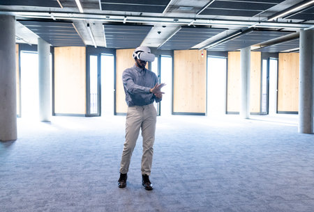 Using VR headset, man exploring virtual environment in modern office space, copy space. Technology, virtual reality, innovation, exploration, digital, immersiveの写真素材