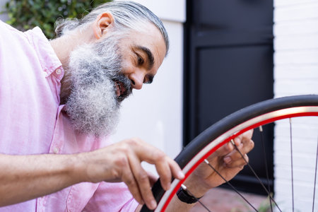 Repairing bicycle tire, man focusing on fixing wheel outside. Cycling, maintenance, outdoors, bike,...