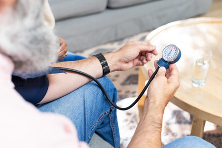 Measuring blood pressure, senior man using sphygmomanometer at home. Healthcare, medical, monitoring, home care, wellness, elderlyの写真素材