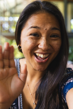 Portrait of happy asian woman with long hair having video call at home. Domestic life, technology and lifestyle, unaltered.の写真素材