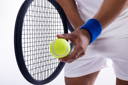 Close-up of a tennis player preparing to serve on a white background. The focus is on the equipment and the anticipation of the game.の写真素材
